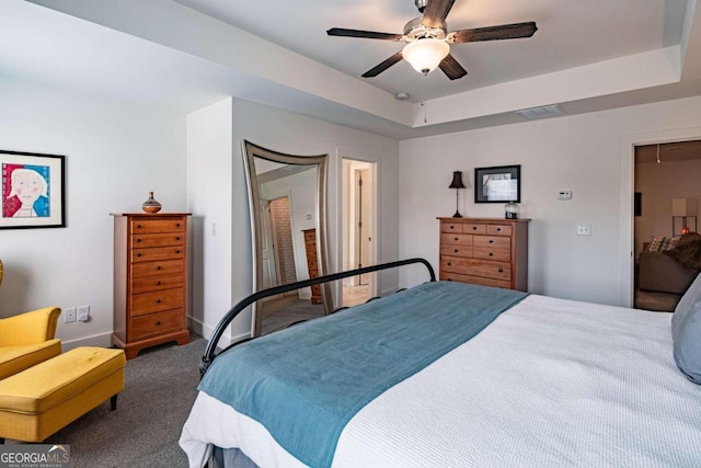 carpeted bedroom with a closet, ceiling fan, and a raised ceiling