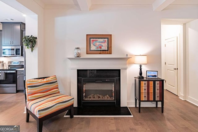 living area with hardwood / wood-style flooring and beam ceiling