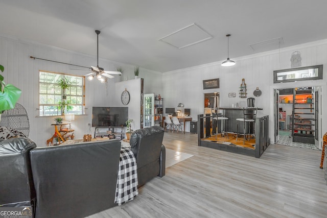 living area featuring a bar, attic access, crown molding, and wood finished floors