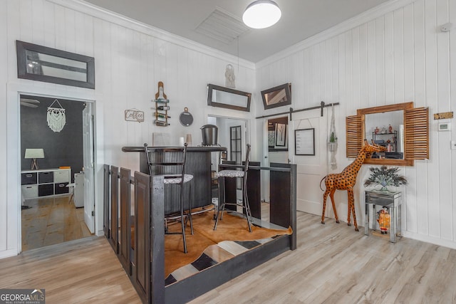 home office featuring ornamental molding, wood finished floors, visible vents, and a barn door