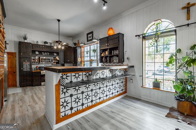 bar with ceiling fan, stainless steel microwave, and light wood-type flooring