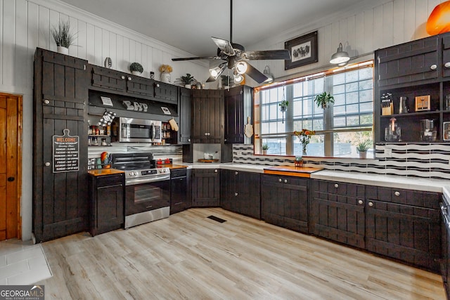 kitchen featuring stainless steel appliances, light wood-style floors, crown molding, and dark brown cabinetry