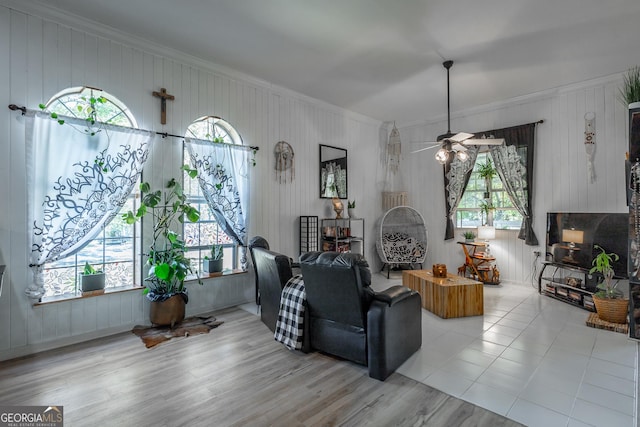 living room featuring a healthy amount of sunlight, ceiling fan, crown molding, and wood finished floors