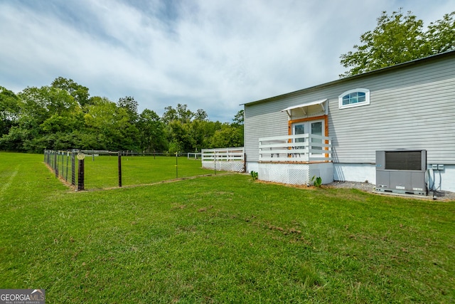 view of yard featuring a deck, central AC, and fence