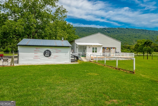 rear view of property featuring a yard, metal roof, and a deck