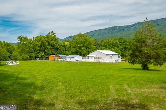 view of yard with a rural view, a mountain view, and fence