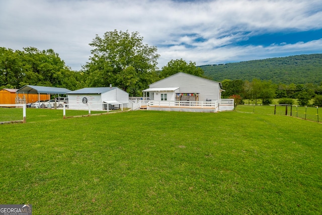 back of house featuring a lawn, fence, and a wooden deck