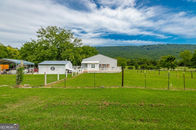 view of yard featuring a forest view, fence, and an outbuilding