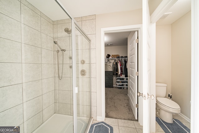 bathroom with an enclosed shower, toilet, and tile patterned flooring