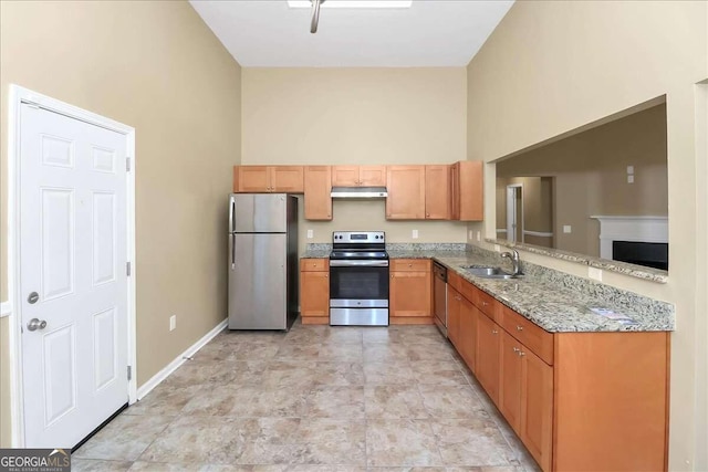 kitchen featuring stainless steel appliances, light tile patterned floors, sink, a high ceiling, and light stone counters