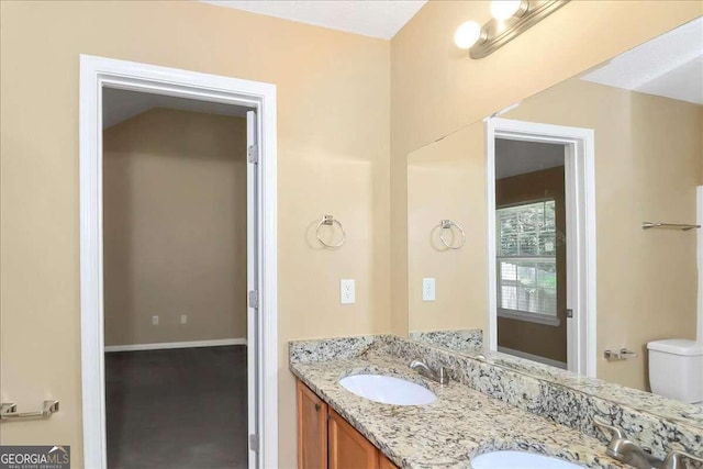 bathroom with dual vanity and toilet