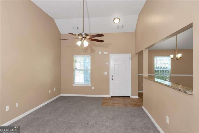 carpeted entrance foyer with ceiling fan with notable chandelier and lofted ceiling