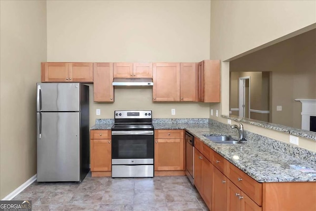 kitchen featuring appliances with stainless steel finishes, a towering ceiling, light stone countertops, light tile patterned floors, and sink