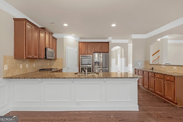 kitchen with tasteful backsplash, crown molding, stainless steel appliances, dark wood-type flooring, and kitchen peninsula