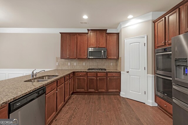 kitchen featuring appliances with stainless steel finishes, dark wood-type flooring, stone countertops, tasteful backsplash, and sink