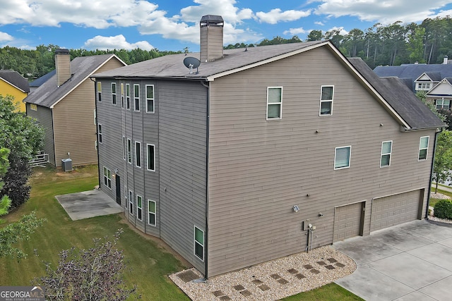 rear view of house featuring cooling unit, a yard, and a garage