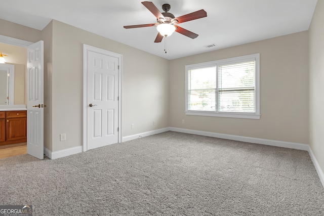 unfurnished bedroom with connected bathroom, ceiling fan, and light carpet