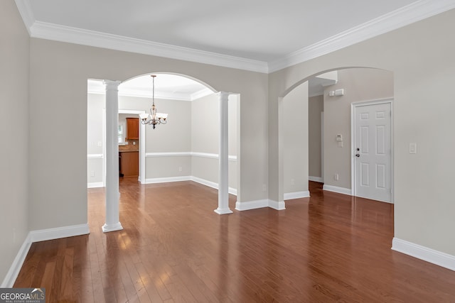 unfurnished room with ornate columns, hardwood / wood-style flooring, a chandelier, and ornamental molding