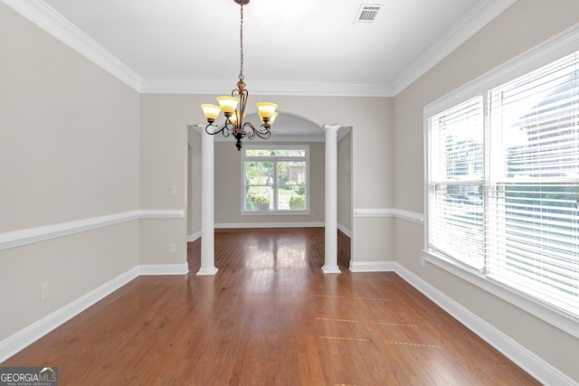 unfurnished dining area featuring hardwood / wood-style floors, decorative columns, crown molding, and an inviting chandelier