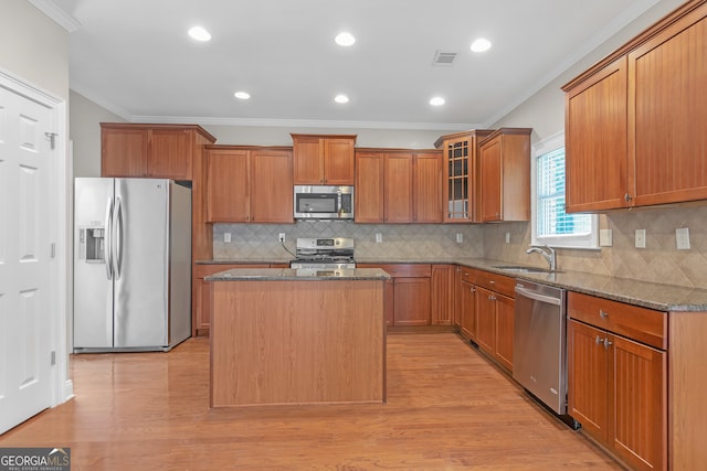 kitchen with dark stone countertops, stainless steel appliances, a center island, and light hardwood / wood-style floors