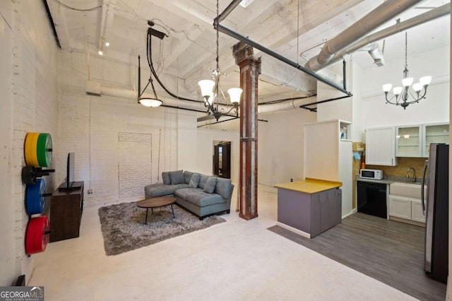 living room with sink, a towering ceiling, hardwood / wood-style flooring, and an inviting chandelier