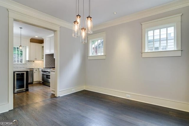 unfurnished dining area featuring plenty of natural light, crown molding, dark wood-type flooring, and beverage cooler