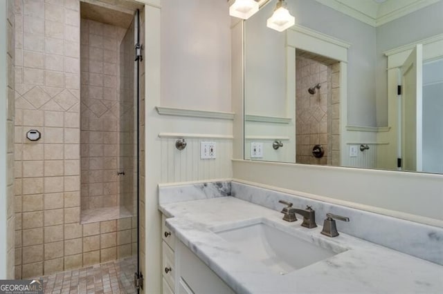 bathroom with a tile shower, ornamental molding, and vanity