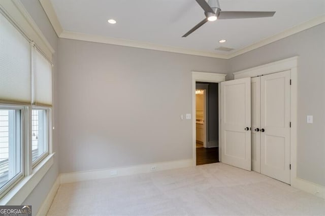 unfurnished bedroom featuring light colored carpet, a closet, crown molding, and ceiling fan