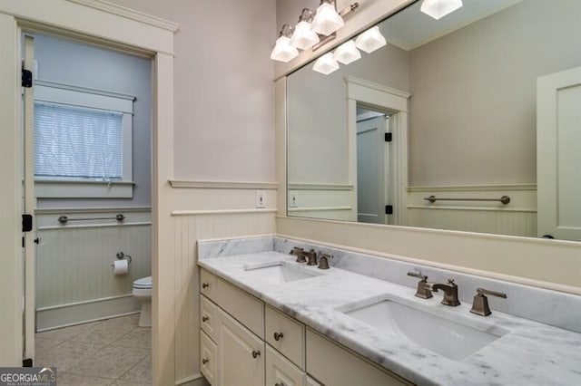 bathroom featuring toilet, double sink vanity, and tile patterned floors