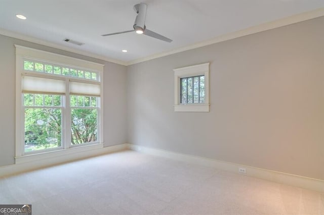 carpeted empty room with ceiling fan, a wealth of natural light, and crown molding