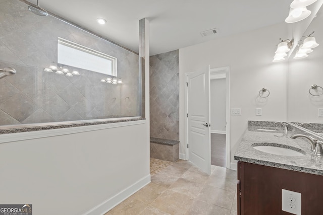 bathroom featuring a tile shower, vanity, and a notable chandelier