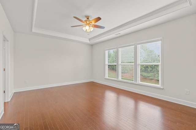 unfurnished room with ceiling fan, ornamental molding, wood-type flooring, and a raised ceiling