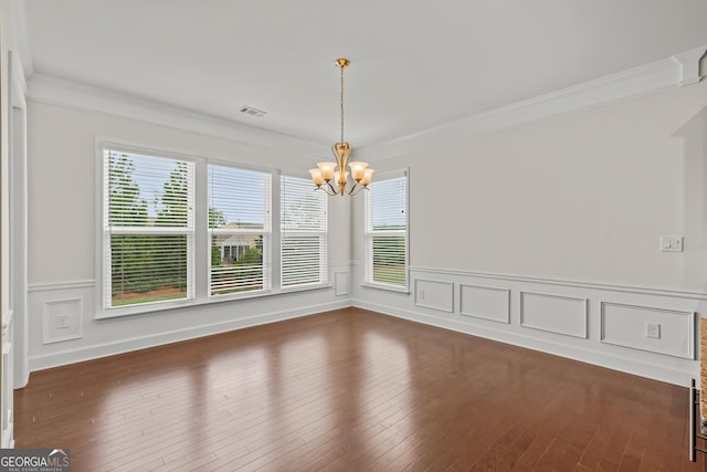 unfurnished dining area featuring dark hardwood / wood-style flooring, crown molding, and an inviting chandelier