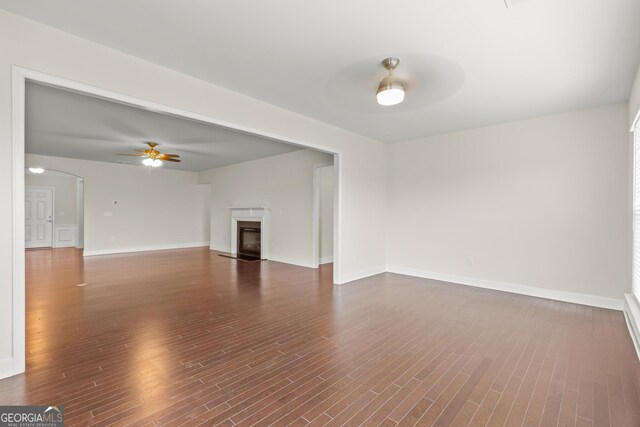 unfurnished living room featuring ceiling fan and dark hardwood / wood-style flooring