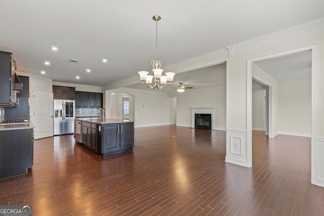 kitchen with a center island with sink, hanging light fixtures, dark brown cabinetry, stainless steel refrigerator with ice dispenser, and ceiling fan with notable chandelier