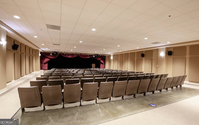 home theater room with a drop ceiling and concrete floors