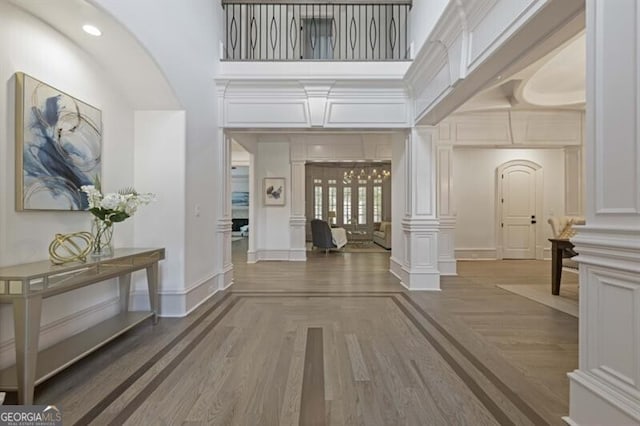 interior space featuring decorative columns, a high ceiling, and wood-type flooring