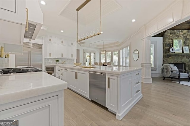 kitchen with a center island, light hardwood / wood-style floors, a stone fireplace, and hanging light fixtures