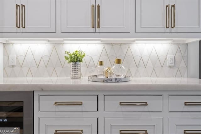 bar featuring light stone countertops, wine cooler, and tasteful backsplash