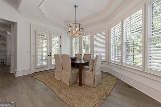 dining space featuring a notable chandelier, plenty of natural light, a tray ceiling, and wood-type flooring