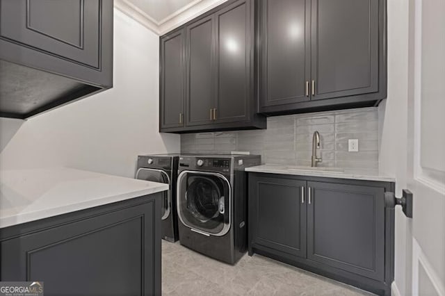 clothes washing area with sink, washing machine and dryer, cabinets, light tile patterned floors, and crown molding