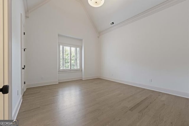 unfurnished room with high vaulted ceiling, ornamental molding, and wood-type flooring