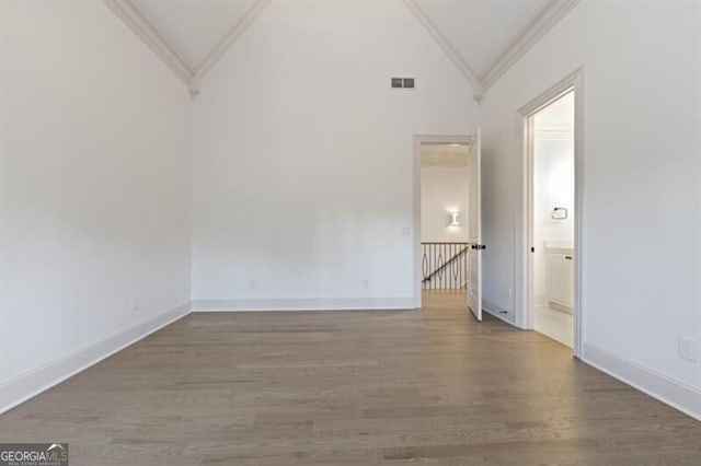 empty room with hardwood / wood-style floors, high vaulted ceiling, and crown molding