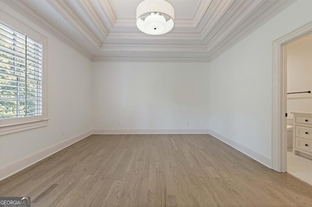 unfurnished room featuring a raised ceiling, crown molding, and light hardwood / wood-style flooring