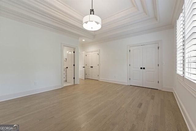 interior space featuring light hardwood / wood-style flooring, crown molding, and a raised ceiling