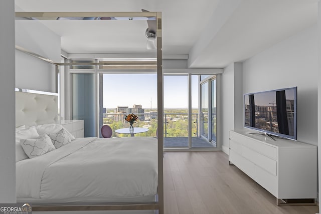 bedroom featuring access to outside, floor to ceiling windows, and wood finished floors