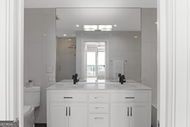 bathroom with tile walls, dual vanity, and toilet