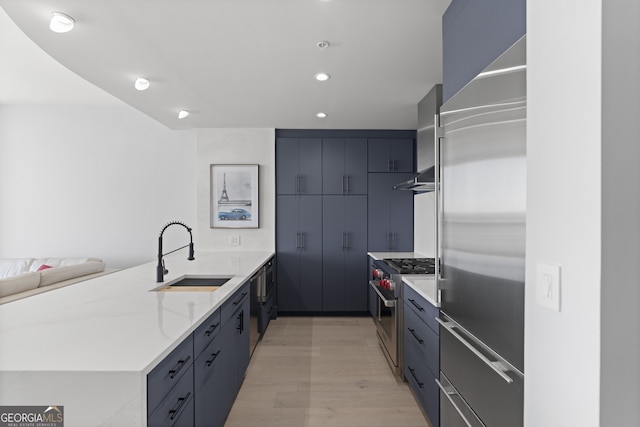 kitchen with modern cabinets, a sink, light stone counters, a peninsula, and high end appliances