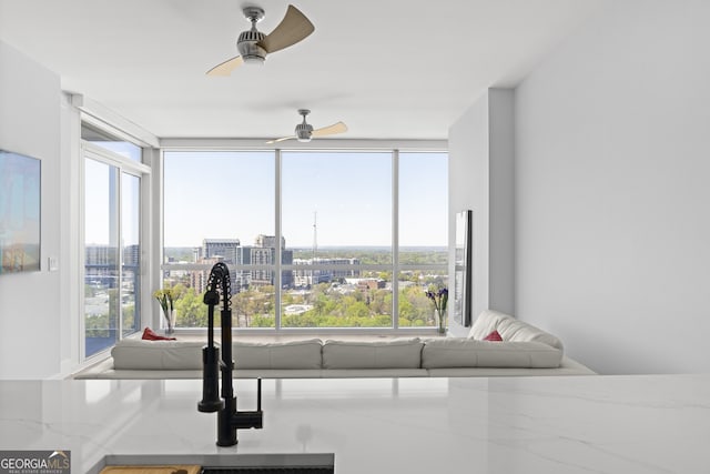 living room with ceiling fan, expansive windows, and a healthy amount of sunlight