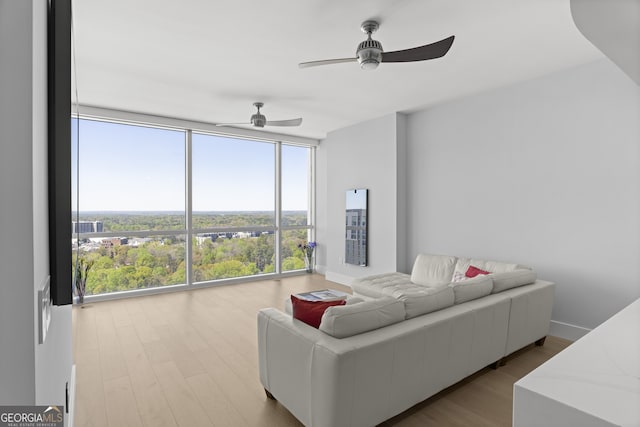 living area featuring floor to ceiling windows, ceiling fan, baseboards, and wood finished floors